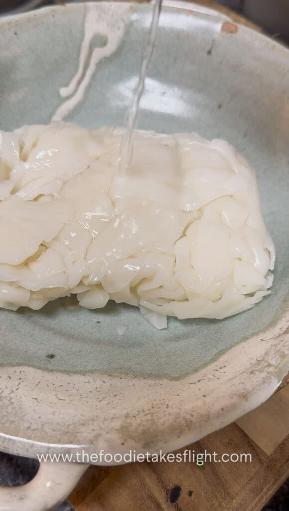 Fresh flat rice noodles being microwaved with a splash of water to loosen them