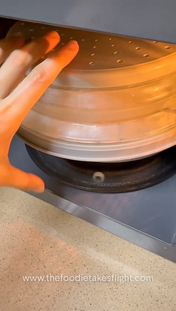 Fresh flat rice noodles being microwaved with a splash of water to loosen them