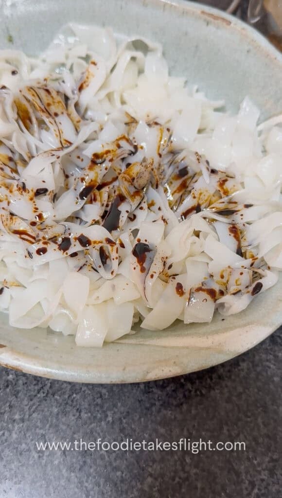 Rice noodles tossed with soy sauce before stir-frying in a wok
