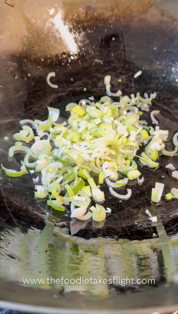 Garlic and green onions sautéing in a wok with oil