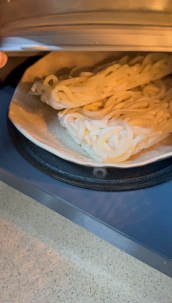 Frozen Sanuki udon noodles being microwaved and separated