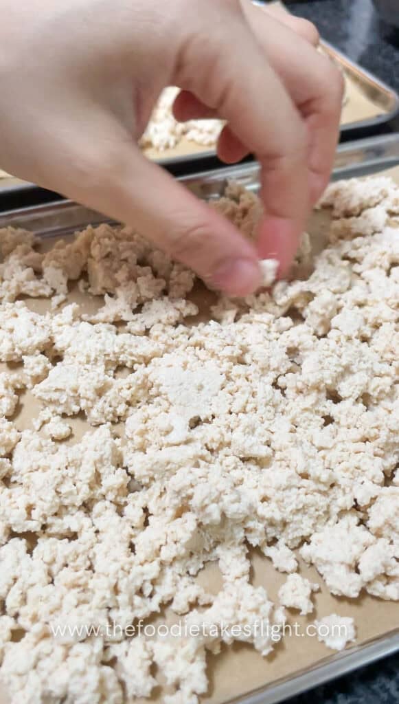 Crumbled tofu spread on a baking tray before baking until golden