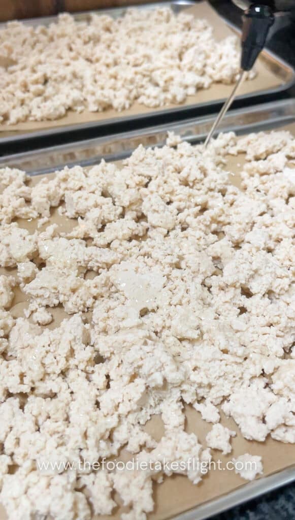 Crumbled tofu spread on a baking tray before baking until golden