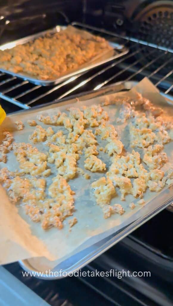 Crumbled tofu spread on a baking tray before baking until golden