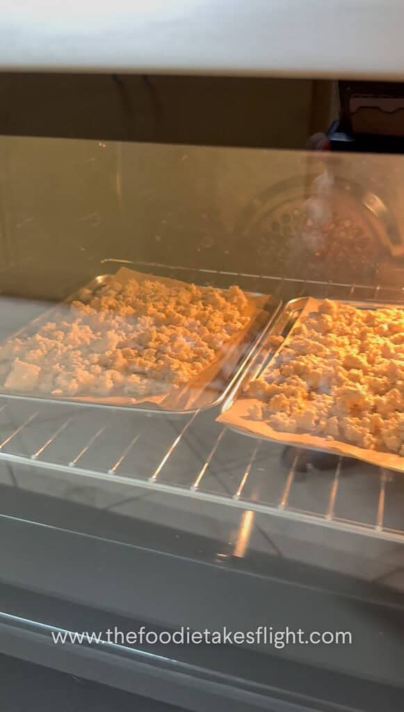 Crumbled tofu spread on a baking tray baking until golden