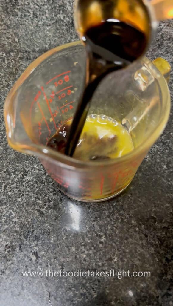 Calamansi juice being mixed with soy sauce and seasonings for noodle sauce