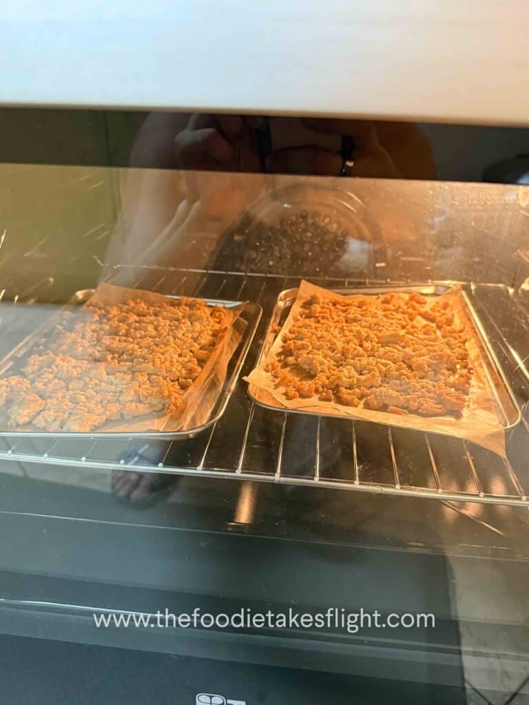 Crumbled tofu spread on a baking tray before baking until golden