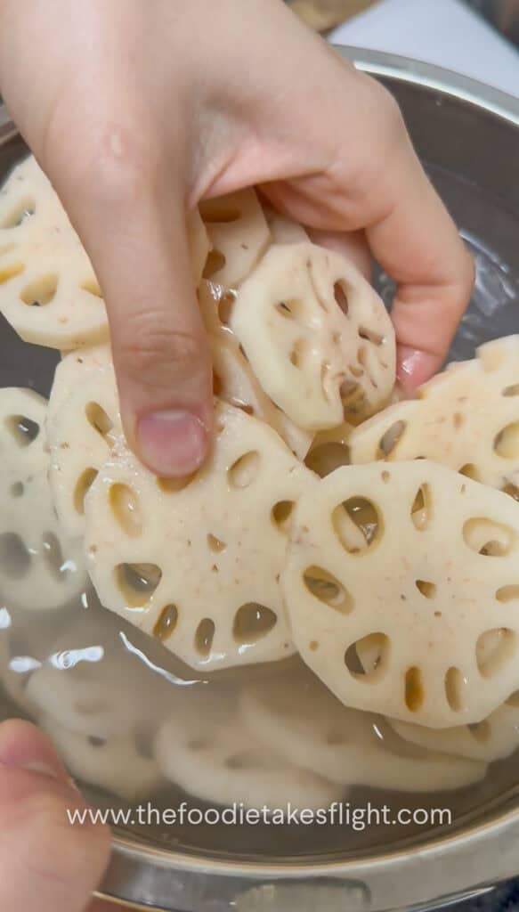 Peeled lotus root sliced into thick rounds and soaking in water with vinegar