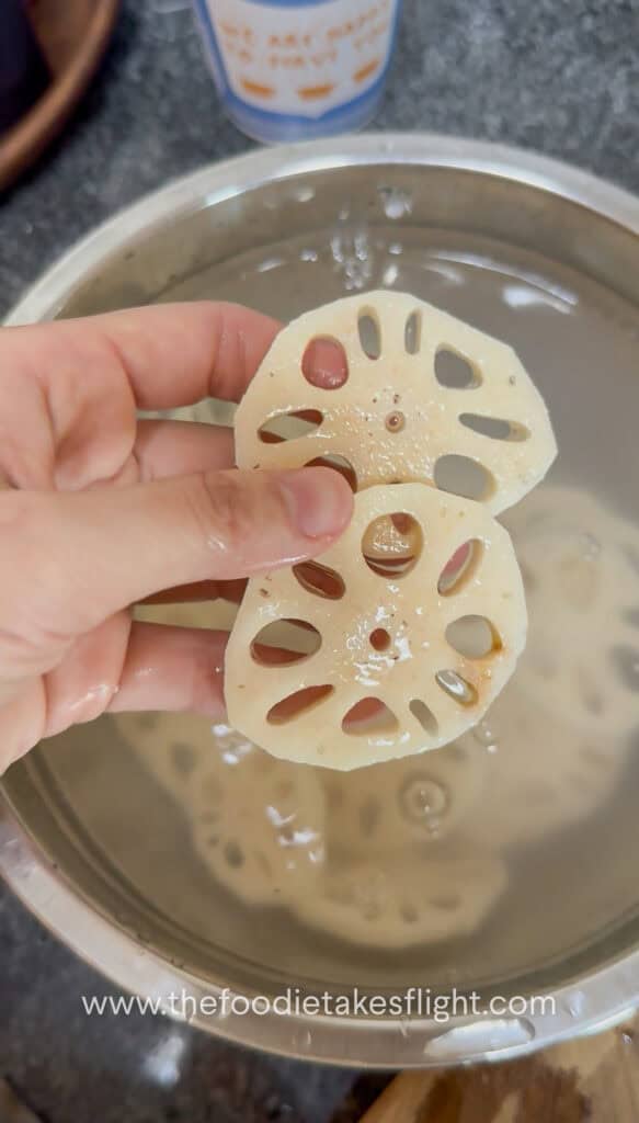Peeled lotus root sliced into thick rounds and soaking in water with vinegar
