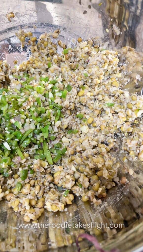 Cooked mung beans being mashed in a bowl with a fork