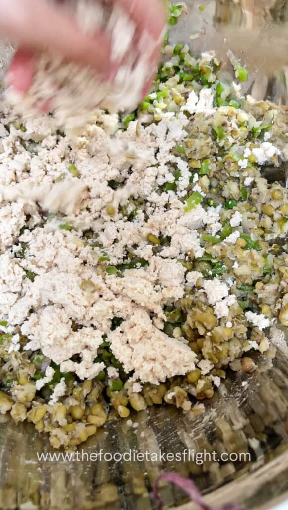 Mung bean and tofu mixture being mixed in a bowl before shaping into patties