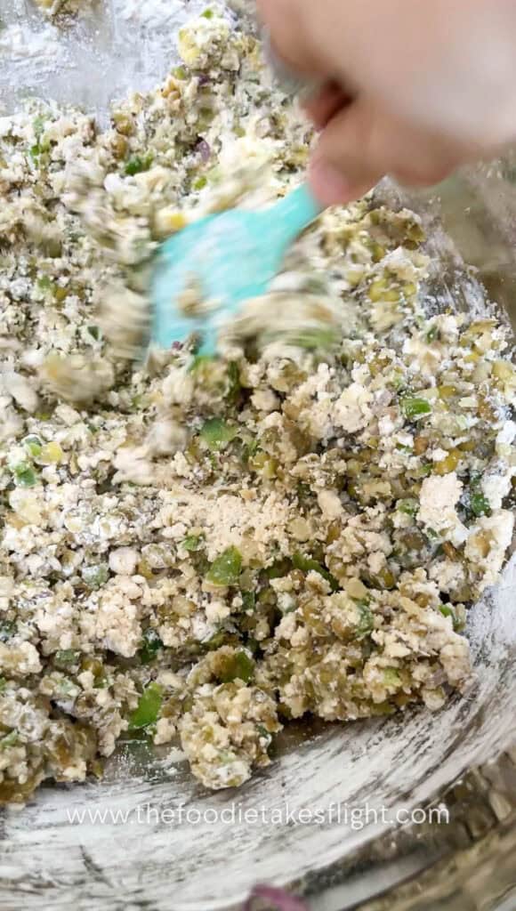 Mung bean and tofu mixture being mixed in a bowl before shaping into patties