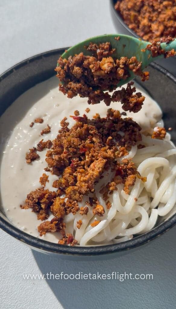 placing tofu crumble over the udon