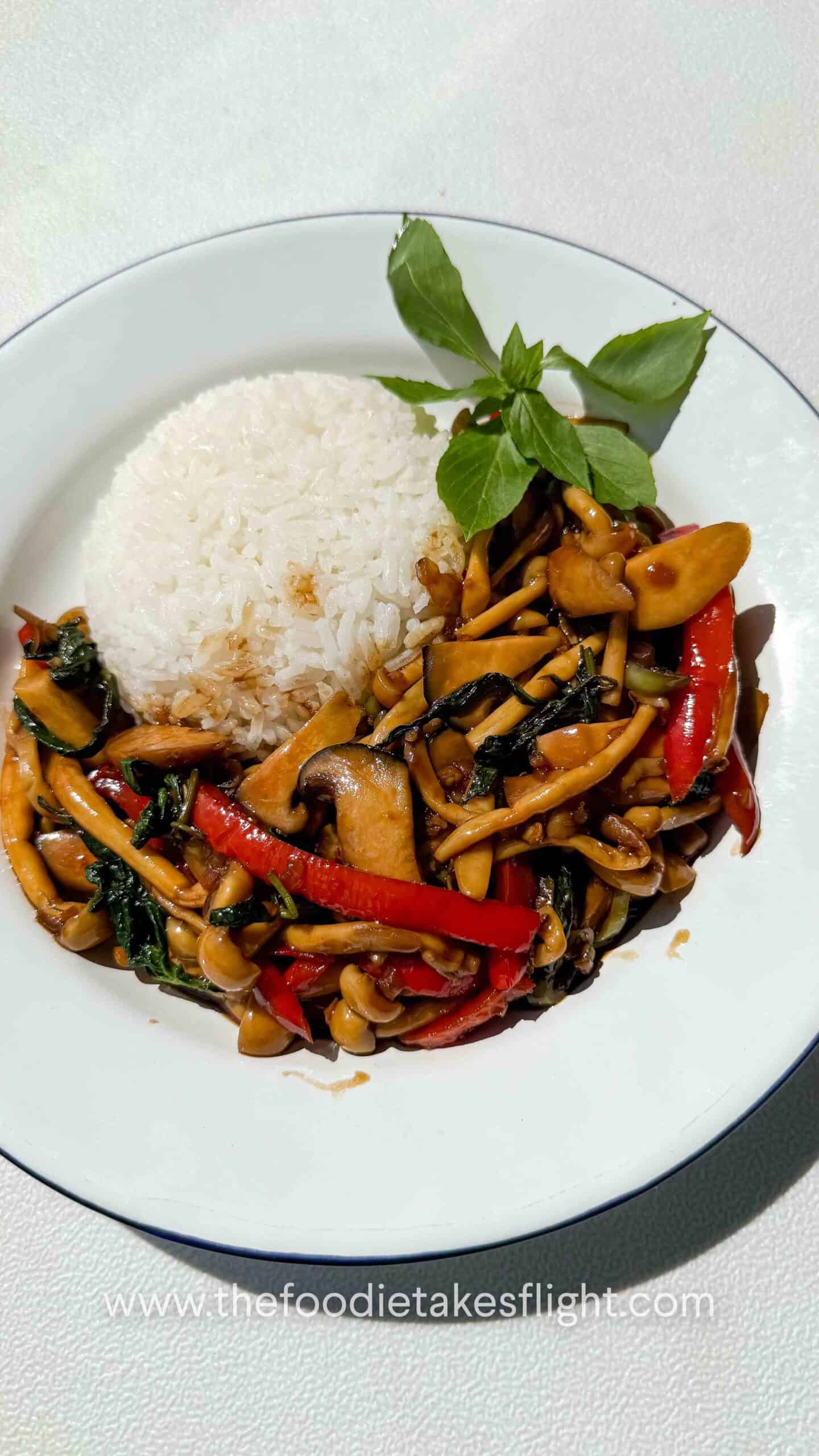 Mushroom kra pao stir-fry with mixed mushrooms, chili, garlic, and basil in a rich savory sauce served with rice