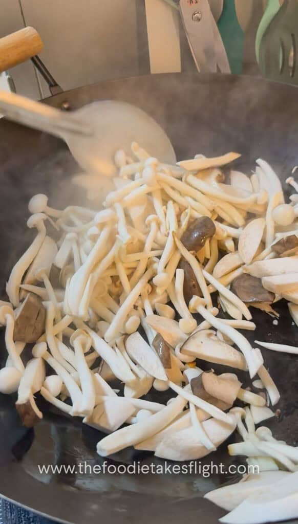 King oyster and shimeji mushrooms cooking in a hot pan until lightly browned