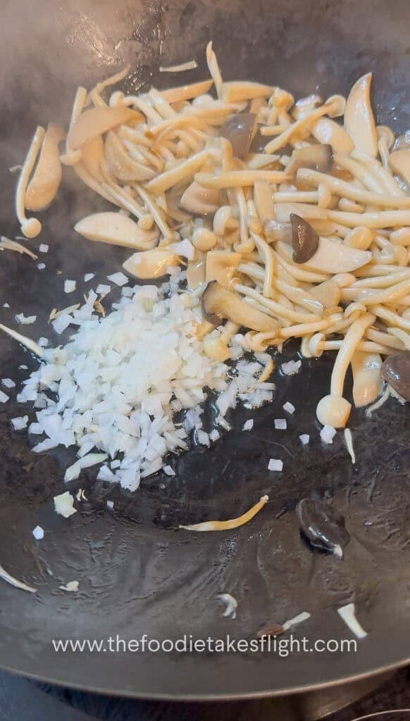Minced garlic, diced onion, and sliced chiles sautéing in oil in a wok