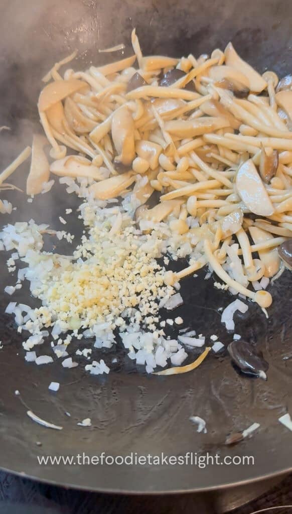 Minced garlic, diced onion, and sliced chiles sautéing in oil in a wok