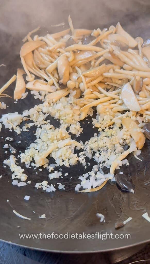 Minced garlic, diced onion, and sliced chiles sautéing in oil in a wok
