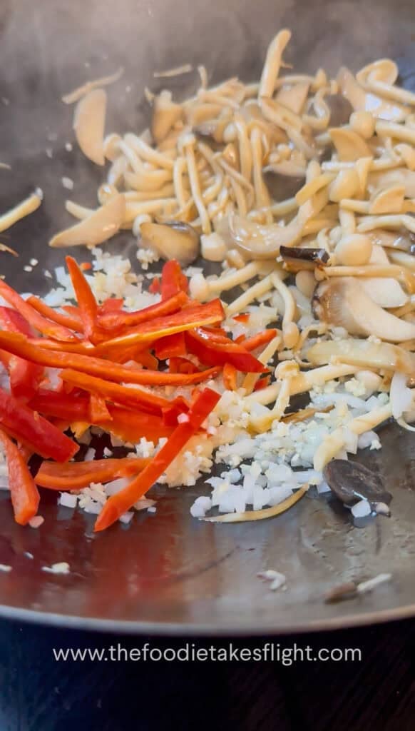 Red bell peppers added to the pan with aromatics for mushroom kra pao
