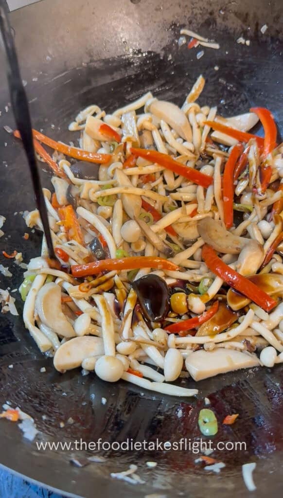 Sauce ingredients coating the mushrooms and vegetables in the wok