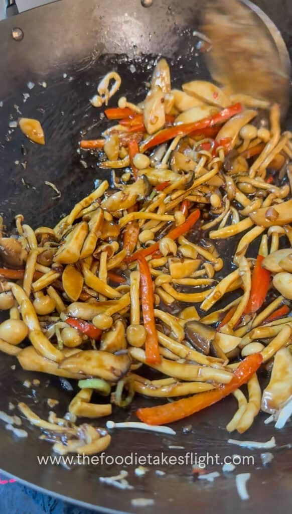 Sauce coating the mushrooms and vegetables in the wok