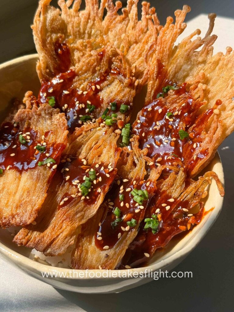 Crispy pan-fried enoki mushrooms served over rice with gochujang sauce, scallions, and sesame seeds