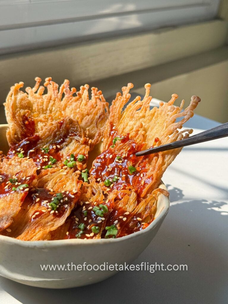 Crispy pan-fried enoki mushrooms served over rice with gochujang sauce, scallions, and sesame seeds