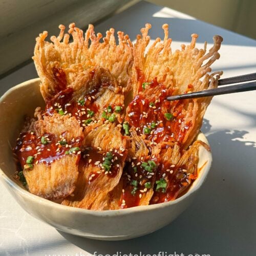 Crispy pan-fried enoki mushrooms served over rice with gochujang sauce, scallions, and sesame seeds