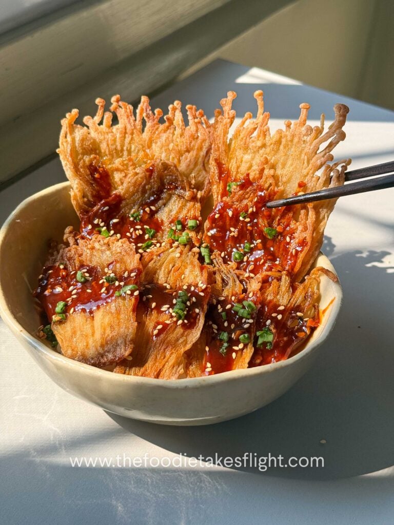 Crispy pan-fried enoki mushrooms served over rice with gochujang sauce, scallions, and sesame seeds