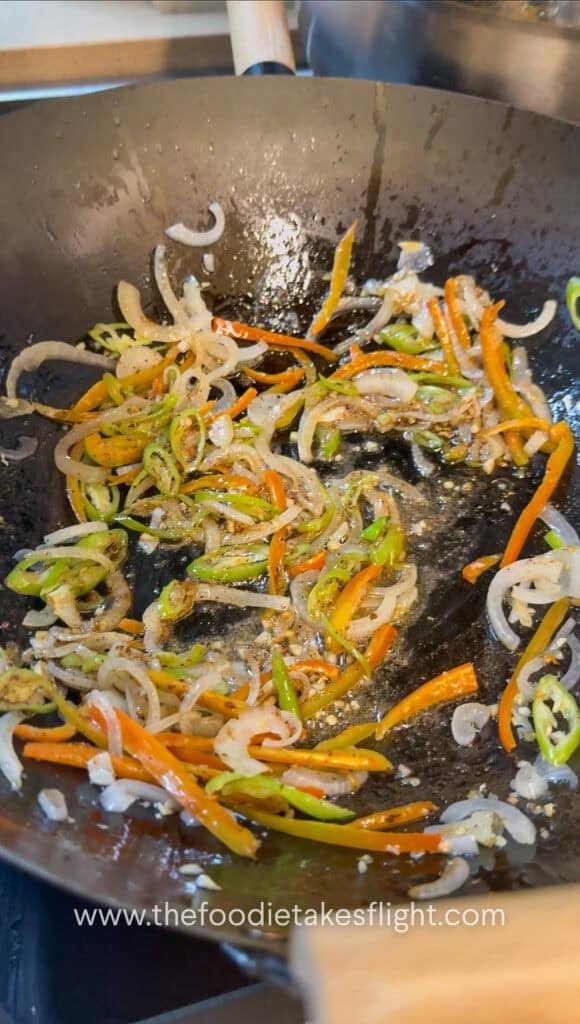 stir-frying aromatics with Sichuan pepper in a steel wok