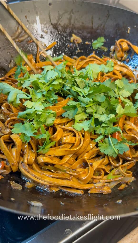 adding cilantro to stir-fried tofu noodles