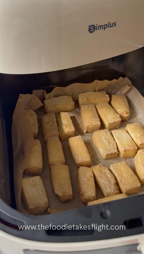 golden air fried tofu on a lined air fryer basket