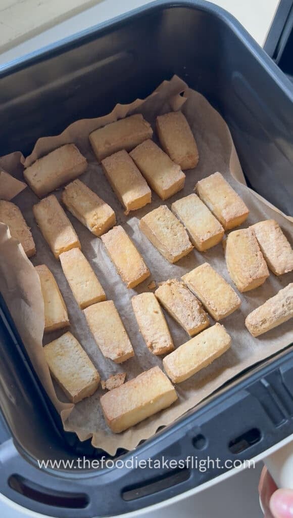 golden air fried tofu on a lined air fryer basket