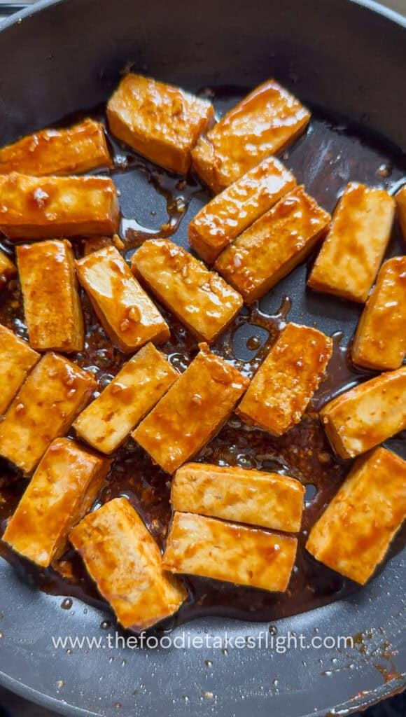 Golden hoisin glazed tofu pieces in a pan