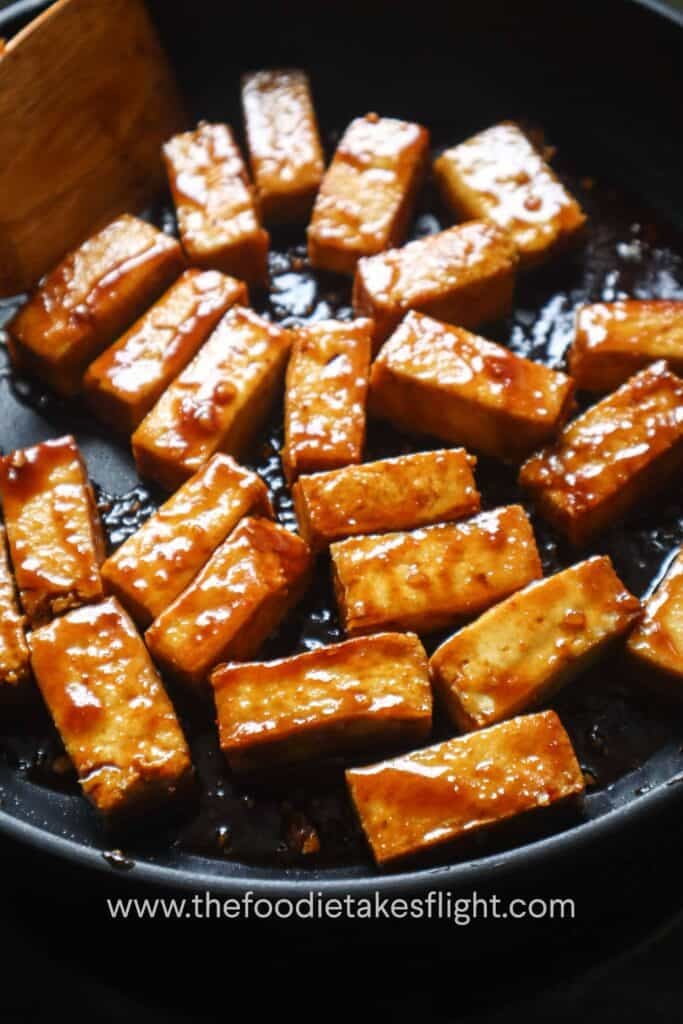 Golden hoisin glazed tofu pieces in a pan