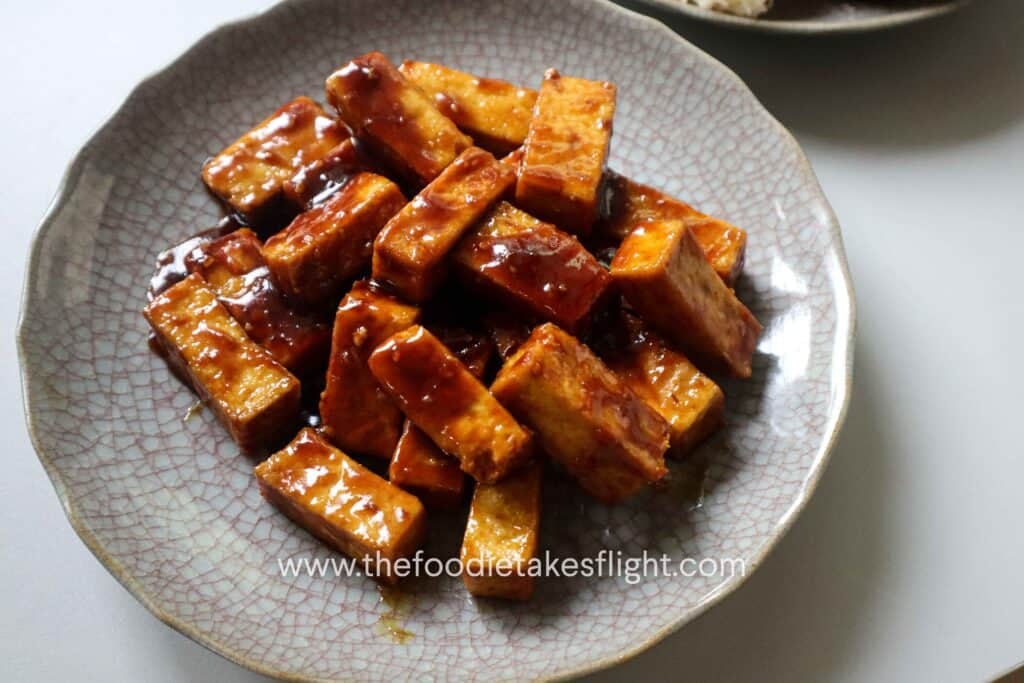 Golden hoisin glazed tofu pieces in a plate