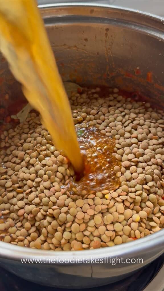 Vegetable broth poured into the pot with lentils and vegetables.