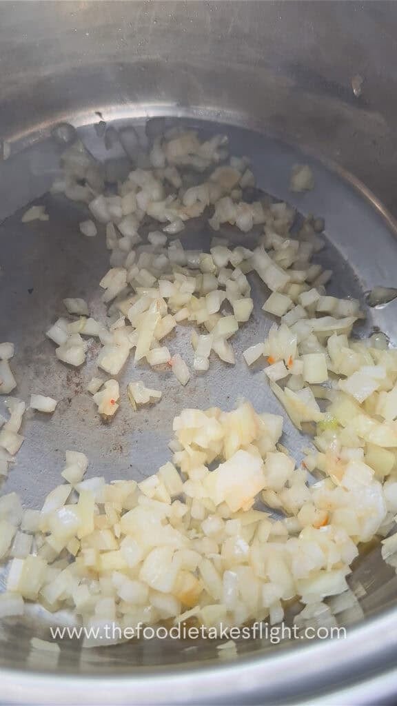 Aromatics and vegetables cooking in a pot for lentil soup.