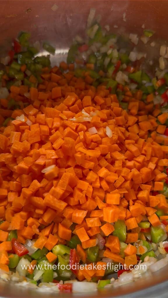 Aromatics and vegetables cooking in a pot for lentil soup.