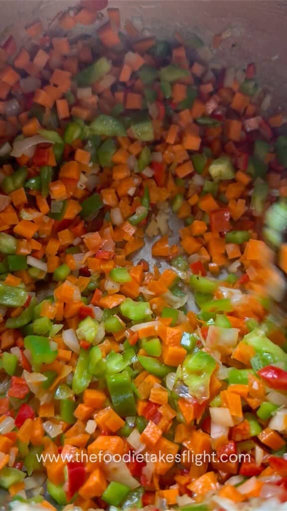 Aromatics and vegetables cooking in a pot for lentil soup.