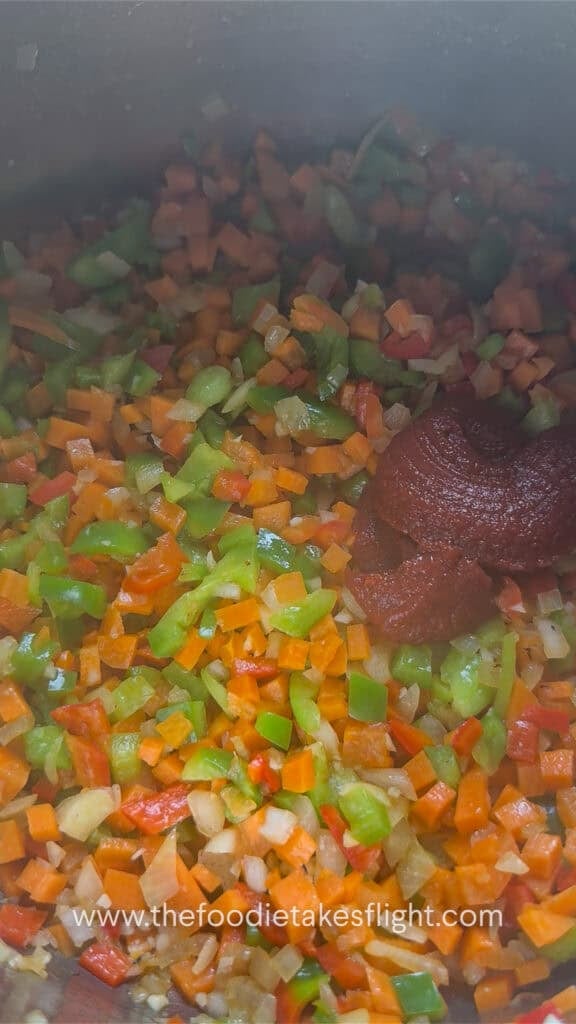 Tomato paste and seasonings added to the sautéed vegetables.