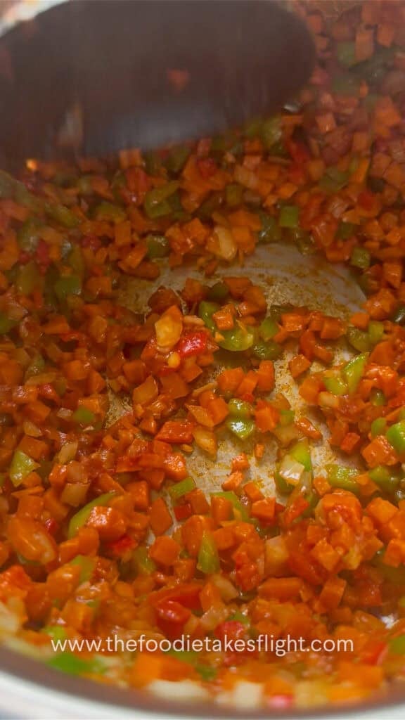 Tomato paste and seasonings added to the sautéed vegetables.