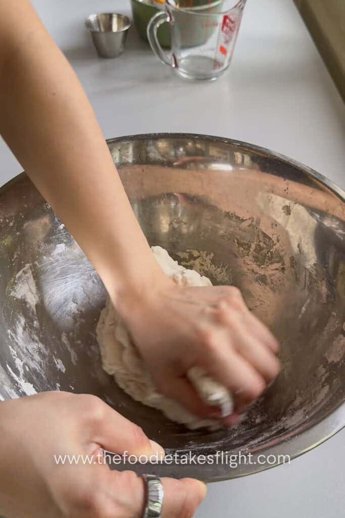 Homemade pita dough being kneaded until smooth, soft, and elastic