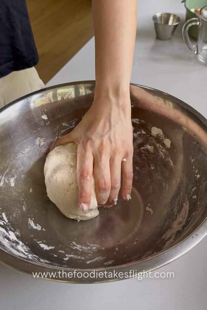Homemade pita dough being kneaded until smooth, soft, and elastic