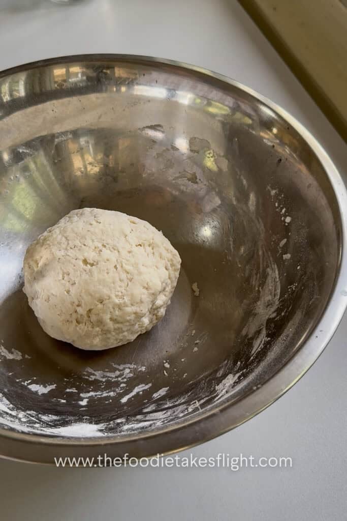 Smooth pita dough ball in a bowl before resting and rising
