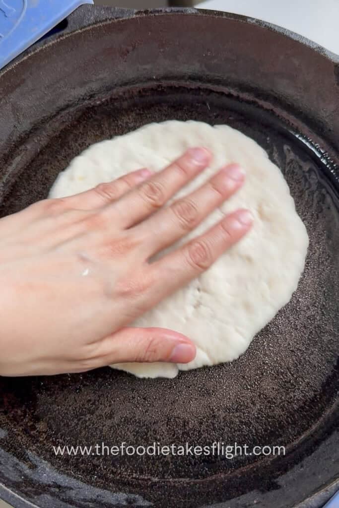 Rolled pita dough cooking on a hot skillet until bubbles form