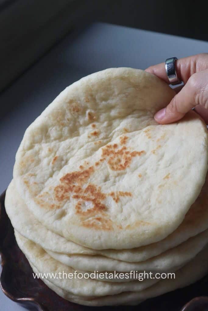 Easy homemade pita bread stacked on a plate with soft, fluffy texture and golden brown spots