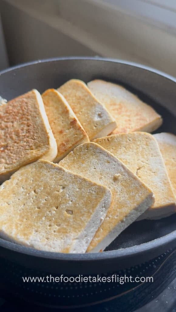Tofu pieces pan-frying until golden brown on both sides