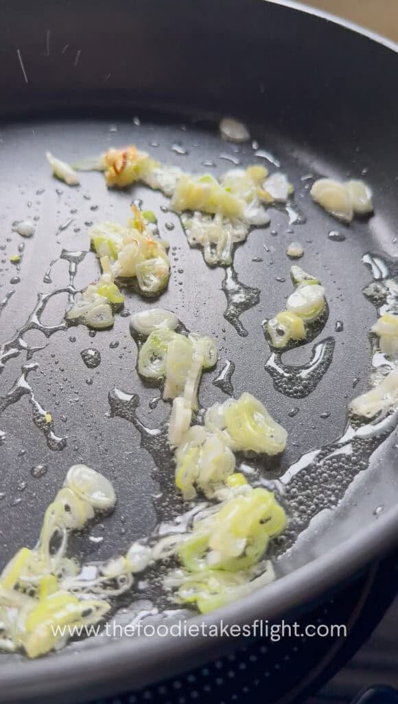 White parts of scallions cooking in neutral oil until aromatic