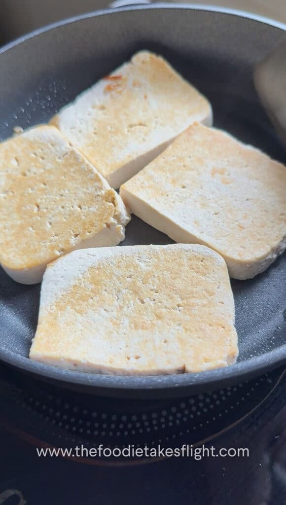 Tofu pieces pan-frying until golden brown on both sides